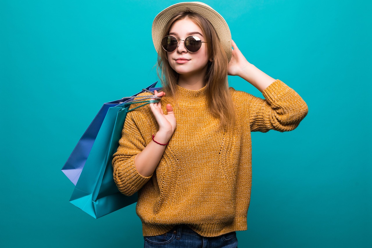7 Web Design Tips to Sell Handmade Items Online | Woman in a straw hat and sunglasses holding paper shopping bags.