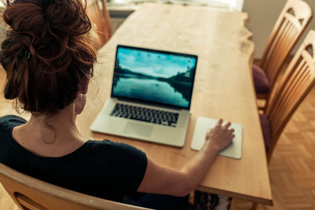 WordPress for Authors: Build a High-Converting Site | Woman sitting at a table using a laptop.