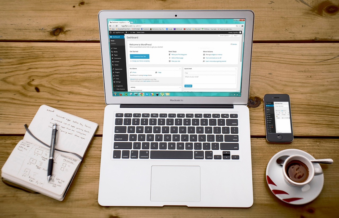 When Do I Need an Author’s Page? | Starting an Author Website Before You Publish | [image of a laptop displaying the WordPress interface beside a notebook and cup of coffee. By We Are Seven